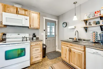 a kitchen with white appliances and wooden cabinets at Steps to Estes Lake Mtn-View Hideaway with Hot Tub! in Estes Park