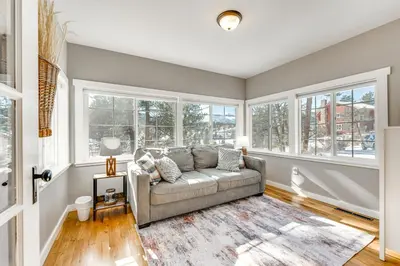a living room with a couch and windows at Steps to Estes Lake Mtn-View Hideaway with Hot Tub! in Estes Park