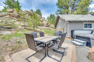 a patio with a table and chairs and a boat at Steps to Estes Lake Mtn-View Hideaway with Hot Tub! in Estes Park