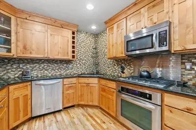 a kitchen with wooden cabinets and stainless steel appliances at The Rustic Retreat, Pet Friendly with Fenced Yard in Fort Collins