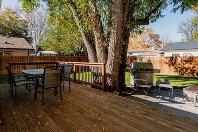 a wooden deck with a table and chairs next to a tree at The Rustic Retreat, Pet Friendly with Fenced Yard in Fort Collins