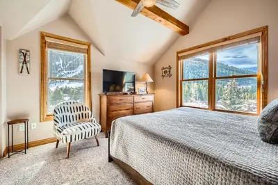 a bedroom with a bed and a chair and windows at 5959 Hidden River Lodge condo in Keystone