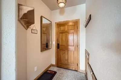 a hallway with a wooden door and a mirror at 5959 Hidden River Lodge condo in Keystone