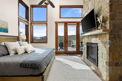 a bedroom with a fireplace and a tv on a stone wall at Ridge View Retreat - Panoramic Views and Hot Tub in Nederland