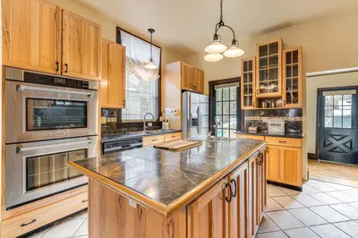 a large kitchen with wooden cabinets and a large island at Historical Dtwn Loveland Home with Wraparound Porch! in Loveland