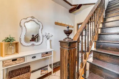 a hallway with a staircase with a mirror and a mirror console at Historical Dtwn Loveland Home with Wraparound Porch! in Loveland