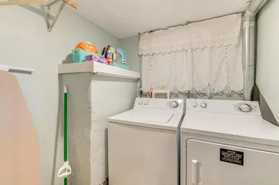 a small laundry room with a washer and dryer at Historical Dtwn Loveland Home with Wraparound Porch! in Loveland