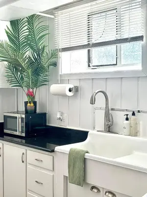 a kitchen with white cabinets and a sink and a plant at 1920s Inspired Stay-coffee Bar- Cozy-local in Denver
