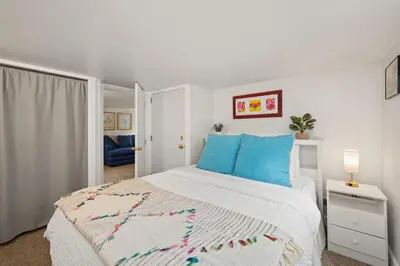 a bedroom with a white bed with blue pillows at Peterson Retreat - Hot Tub, Bikes, Old Town in Fort Collins