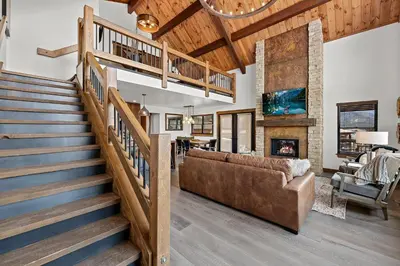 a staircase in a living room with a couch and a fireplace at Cabin on Lake Estes! Private Jacuzzi Two Patios Indoor and Outdoor Fireplace in Estes Park