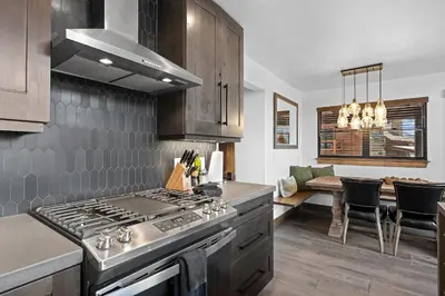 a kitchen with a stove and a dining room at Cabin on Lake Estes! Private Jacuzzi Two Patios Indoor and Outdoor Fireplace in Estes Park