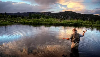 a man standing in a river holding a fish at Cabin on Lake Estes! Private Jacuzzi Two Patios Indoor and Outdoor Fireplace in Estes Park
