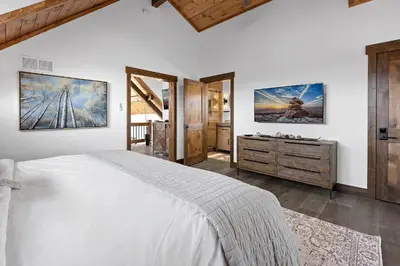 a bedroom with a large white bed and a dresser at Cabin on Lake Estes! Private Jacuzzi Two Patios Indoor and Outdoor Fireplace in Estes Park