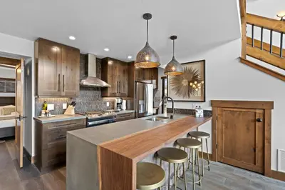 a kitchen with wooden cabinets and a large island with bar stools at Fantastic Views Two Large Patios Private Jacuzzi and Indoor Outdoor Fireplace in Estes Park