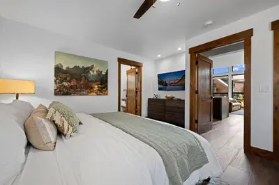 a bedroom with a white bed with a painting on the wall at Fantastic Views Two Large Patios Private Jacuzzi and Indoor Outdoor Fireplace in Estes Park