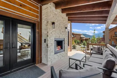 a patio with a stone fireplace on a house at Fantastic Views Two Large Patios Private Jacuzzi and Indoor Outdoor Fireplace in Estes Park