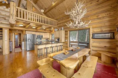 a log cabin kitchen with a dining table and a chandelier at Mounticello Log Cabin - Relaxing Front Patio & Outdoor Firepit in Estes Park