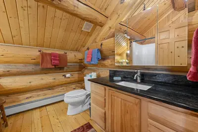 a log cabin bathroom with a toilet and a sink at Mounticello Log Cabin - Relaxing Front Patio & Outdoor Firepit in Estes Park