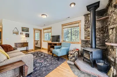 a living room with a fireplace and a stone wall at Moon Creek Cabin cabin in Nederland