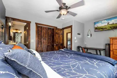 a bedroom with a blue bed with a ceiling fan at Lux 3BR Home - Wildlife & Views near RMNP in Estes Park