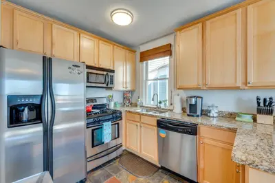 a kitchen with wooden cabinets and a stainless steel refrigerator at 1 Mi to CU Boulder Condo Near Pearl Street! in Boulder