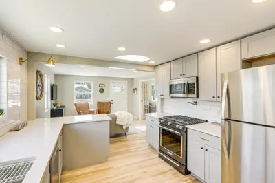 a kitchen with white cabinets and a stainless steel refrigerator at Less Than 1 Mi to Olde Town Arvada Home with Patio! in Arvada