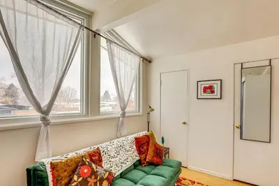 a living room with a green couch and a window at 10 Mi to Red Rocks Denver Home with Fire Pit! in Denver