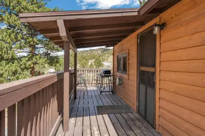 a wooden deck with a table and chairs on it at Yogi Bear's Jellystone Park Camp-Resort in Estes Park in Estes Park