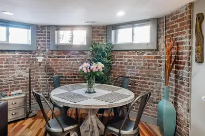 a dining room with a table with chairs and a brick wall at Designer Apartment in a Historic 1901 Downtown Area Mansion in Denver