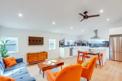 a living room and kitchen with a blue couch and orange chairs at Less Than 1 Block to City Park New-Build Apt in Denver! in Denver