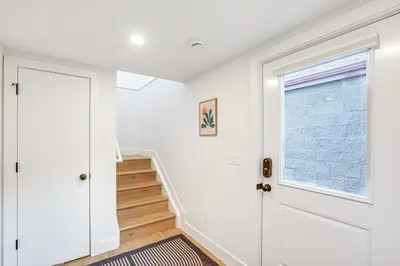 a hallway with white walls and a window and a staircase at Less Than 1 Block to City Park New-Build Apt in Denver! in Denver