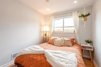 a bedroom with a bed with an orange blanket and a window at Boho Cozy House with bikes, 2 blocks to Sloans Lake! in Denver
