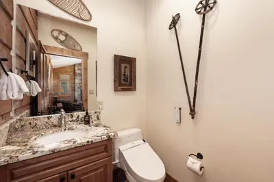 a bathroom with a sink and a toilet and a mirror at 19th Hole cabin in Granby