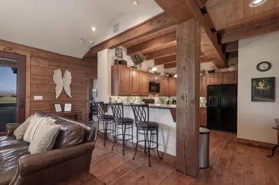 a living room with a couch and a bar with stools at 19th Hole cabin in Granby