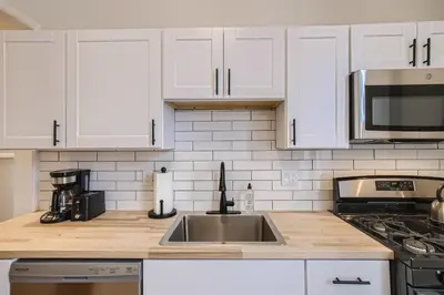 a kitchen with white cabinets and a stainless steel sink at Cloud by Modern Midstay - 1 Block to City Park #C1 in Denver