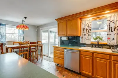 a kitchen with wooden cabinets and a table and chairs at 12 Mi to Dtwn Denver Home with Fenced Backyard! in Northglenn