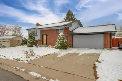a brick house with a garage in the snow at 12 Mi to Dtwn Denver Home with Fenced Backyard! in Northglenn
