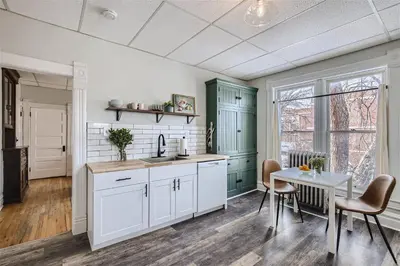 a kitchen with white and green cabinets and a table at Cloud by Modern Midstay - 1 Block to City Park #C5 in Denver