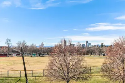 a field with trees and a city in the background at Detroit by Modern Midstay - On City Park #T22 in Denver