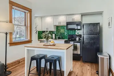 a kitchen with a counter with stools and a refrigerator at 1st Ave by Modern Midstay - Wash Park & SoBo #F2 in Denver