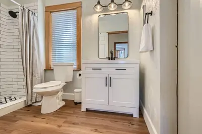 a white bathroom with a toilet and a mirror at 1st Ave by Modern Midstay - Wash Park & SoBo #F2 in Denver