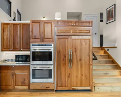 a kitchen with wooden cabinets and a staircase at Pineview Panorama Luxe Retreat 20 Mins to Boulder in Jamestown