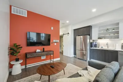 a living room with an orange accent wall at Southwestern Charm Studio at Espadin in Denver