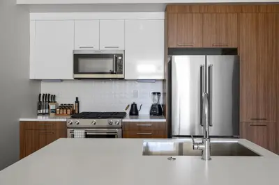 a kitchen with a stainless steel refrigerator and wooden cabinets at Art Inspired Retreat at Espadin in Denver