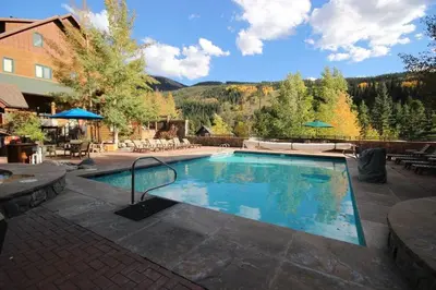a large swimming pool in a patio with a mountain at Luxury 2 bed 2 bath Condo in River Run with Pool and Hot Tub in Keystone