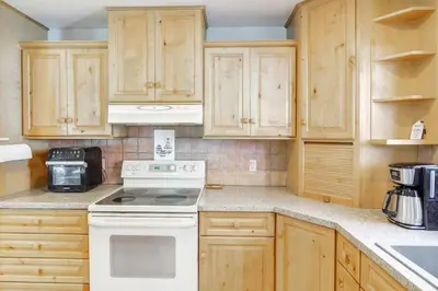 a kitchen with wooden cabinets and a white stove top oven at The Evergreen Oasis I Red Rocks I Morrison in Morrison