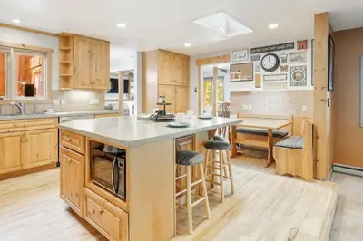 a kitchen with wooden cabinets and a large island with bar stools at The Evergreen Oasis I Red Rocks I Morrison in Morrison