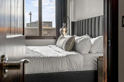 a bedroom with a bed with white sheets and a window at Chic Loft Heart of RiNo in Denver