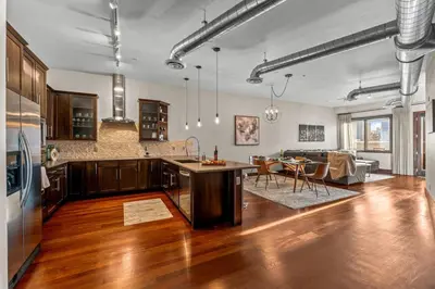 a kitchen and living room with wooden floors and a table at Chic Loft Heart of RiNo in Denver