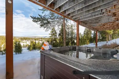 an outdoor deck with a hot tub in the snow at Stunning Mountain Retreat with View and Private Hot Tub in Tabernash